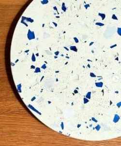 Sous-plat Verrazzo – Mix Vert et Mix+ Bleu Plongez dans l’élégance durable avec nos sous-verres Verrazzo, créations artisanales de Re-Verre. Chaque pièce, d’un diamètre de 20 cm et d’une épaisseur de 0,8 à 1 cm, combine un mélange minéral et des fragments de verre recyclé dans des nuances uniques : le Mix Vert pour une touche naturelle et le Mix+ Bleu pour une note fraîche et contemporaine.